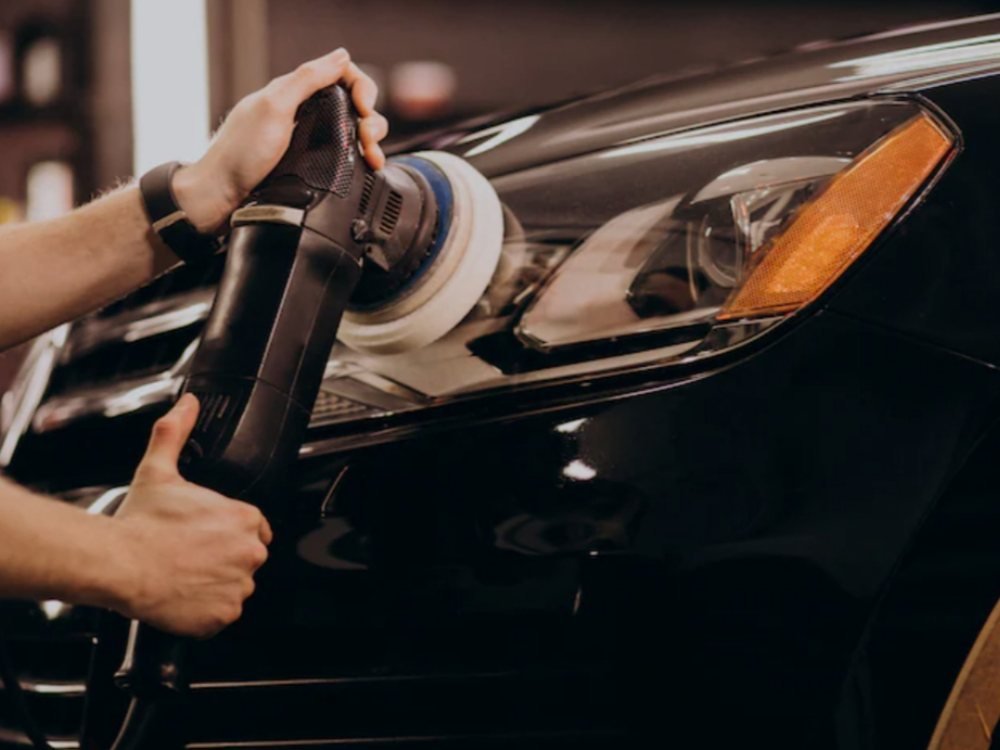 Profissional restaurando o farol de um carro com politriz